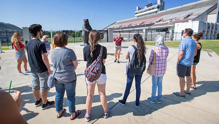MSU student tour guide speaking to visitors next to football stadium