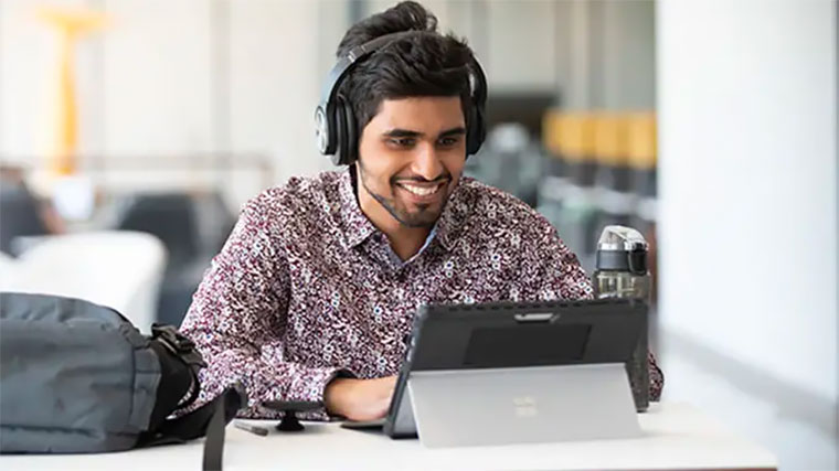 Student walking past a business class with stock market ticker on display